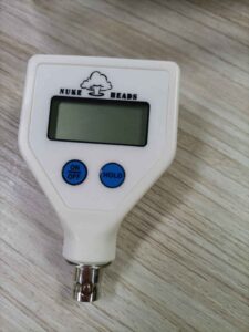 A digital tire pressure gauge on a wooden surface.